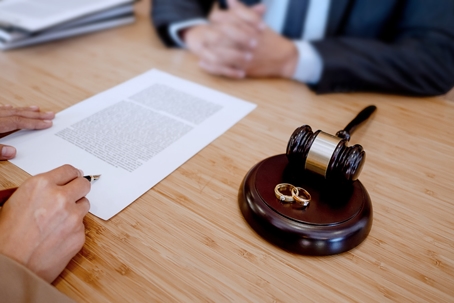 person signing divorce settlement with a lawyer
